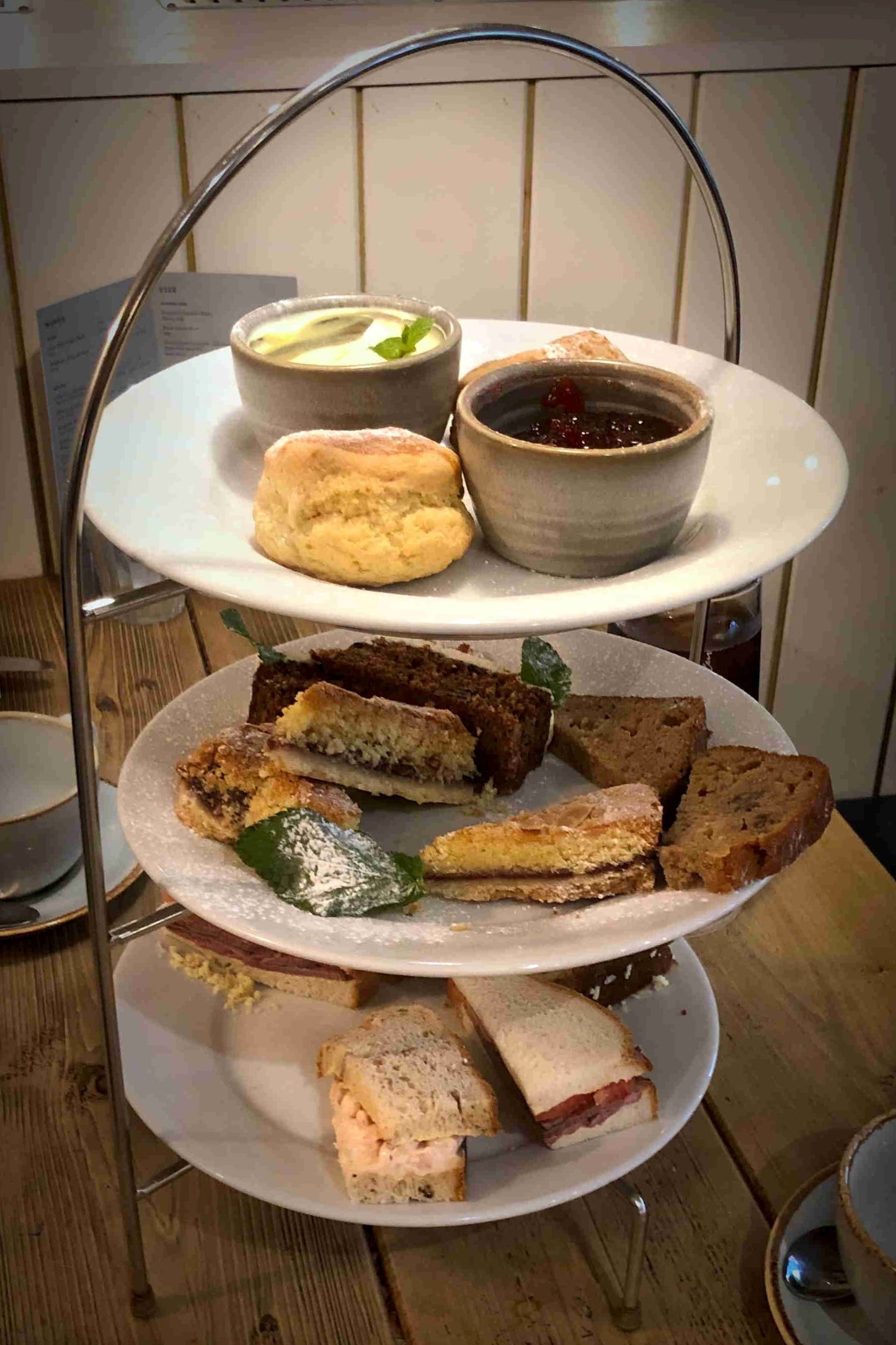 Three-tiered tray with assorted finger foods on a wooden table.